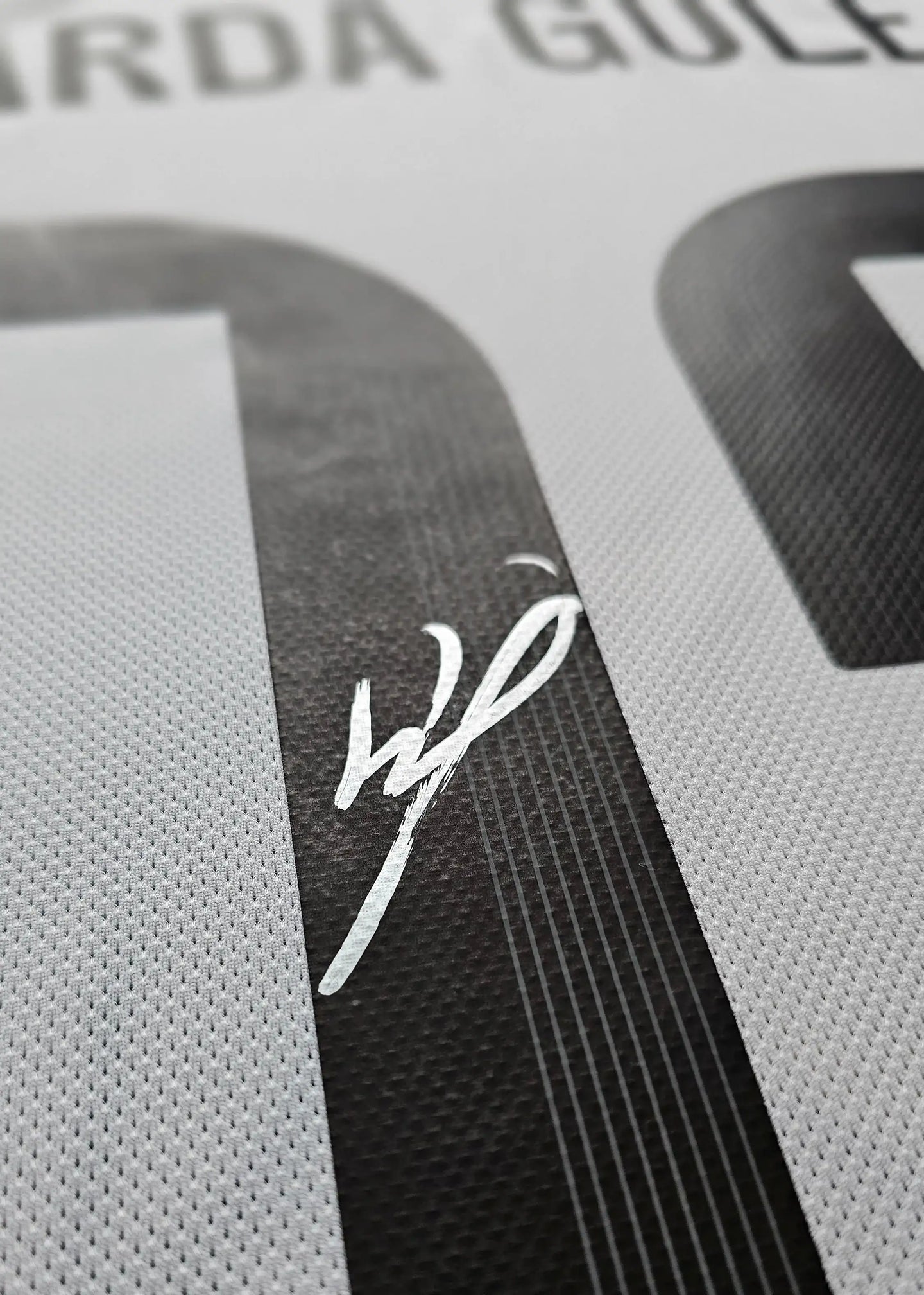 Signature detail of Arda Güler on the number 7 of a white football shirt.