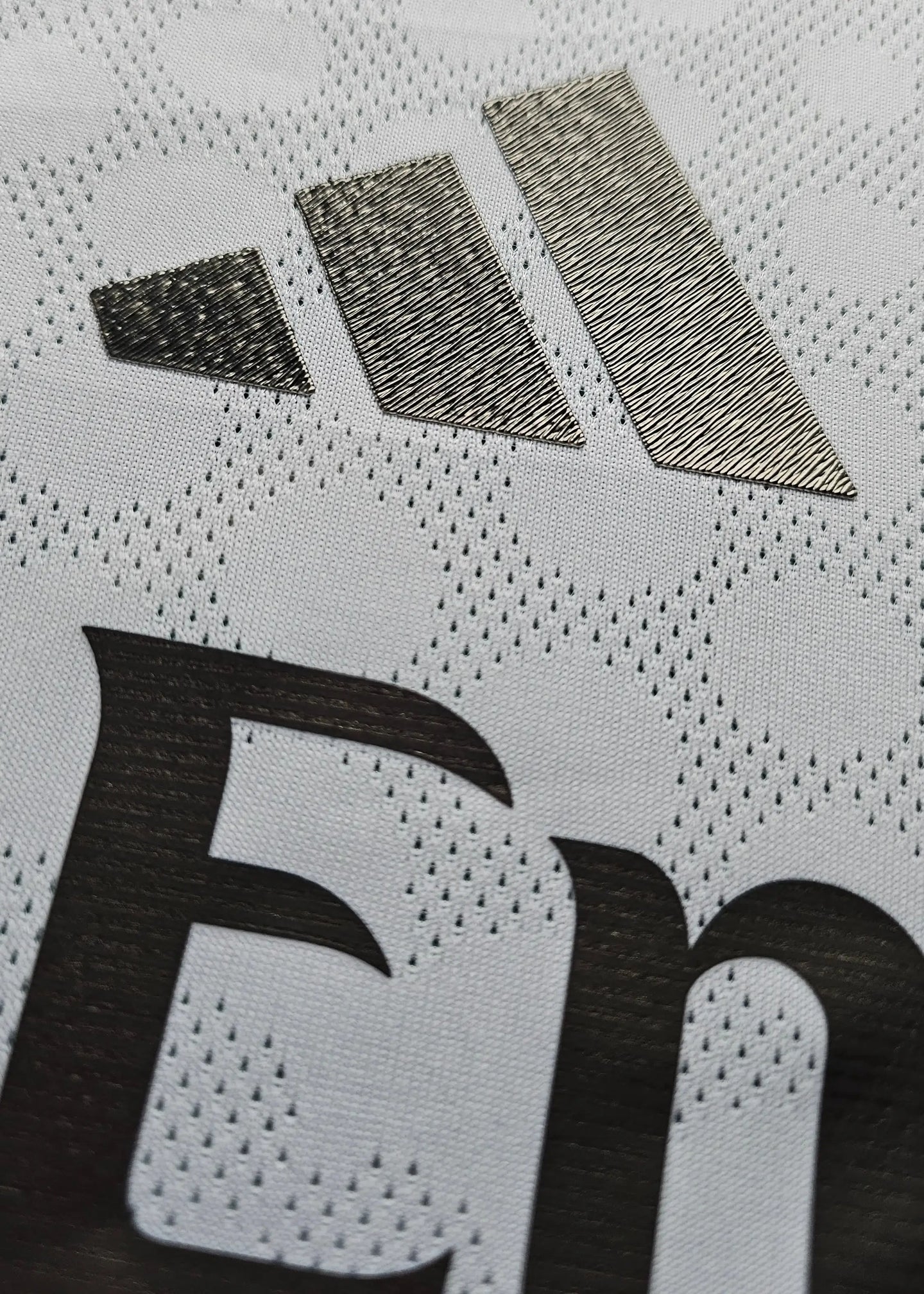 Close-up of the white fabric featuring the adidas logo and the Real Madrid lettering.