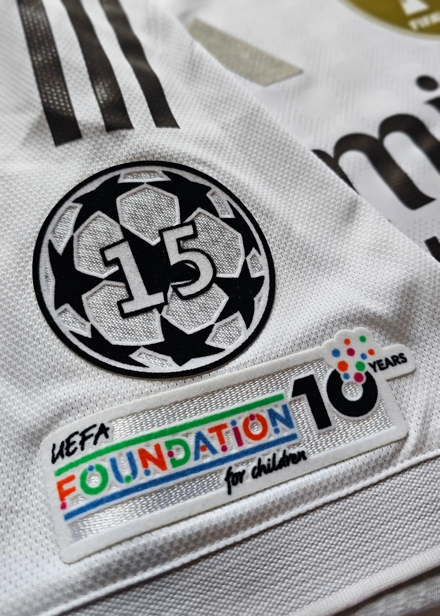 Close-up view showing the UEFA Foundation patch and No. 15 emblem on the white football shirt.