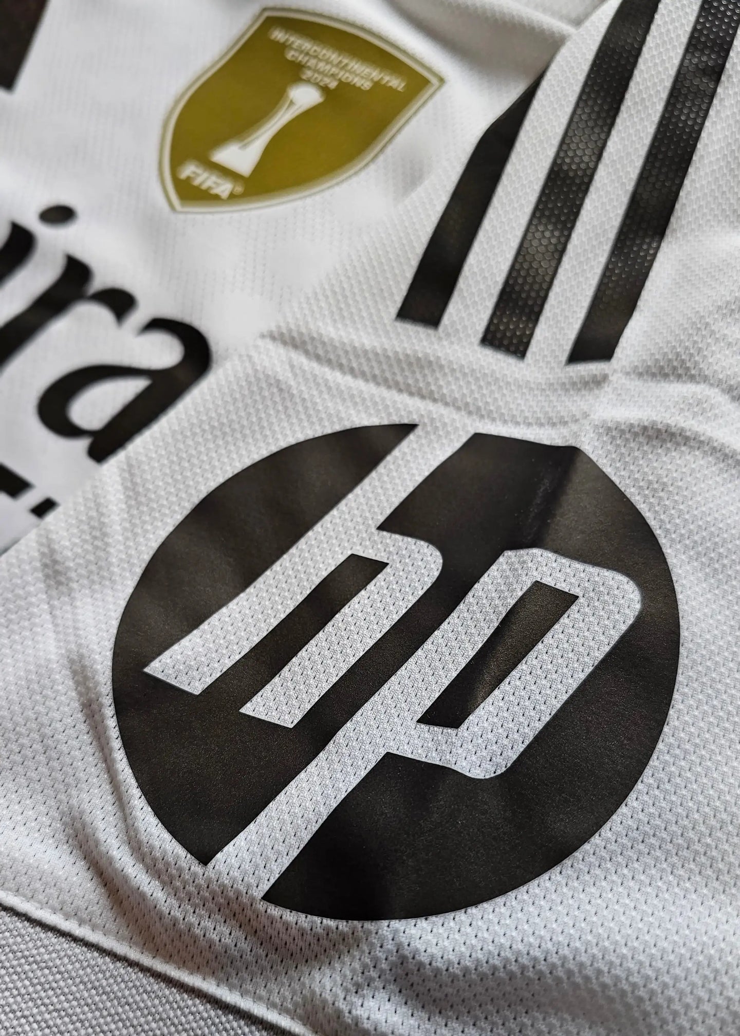Detail view showing the FIFA Intercontinental Champions badge and HP sponsor logo on a signed football shirt.