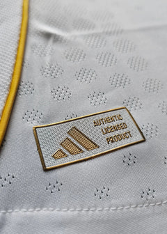Close-up detail of the adidas logo and the text AUTHENTIC LICENSED PRODUCT on a white football shirt.