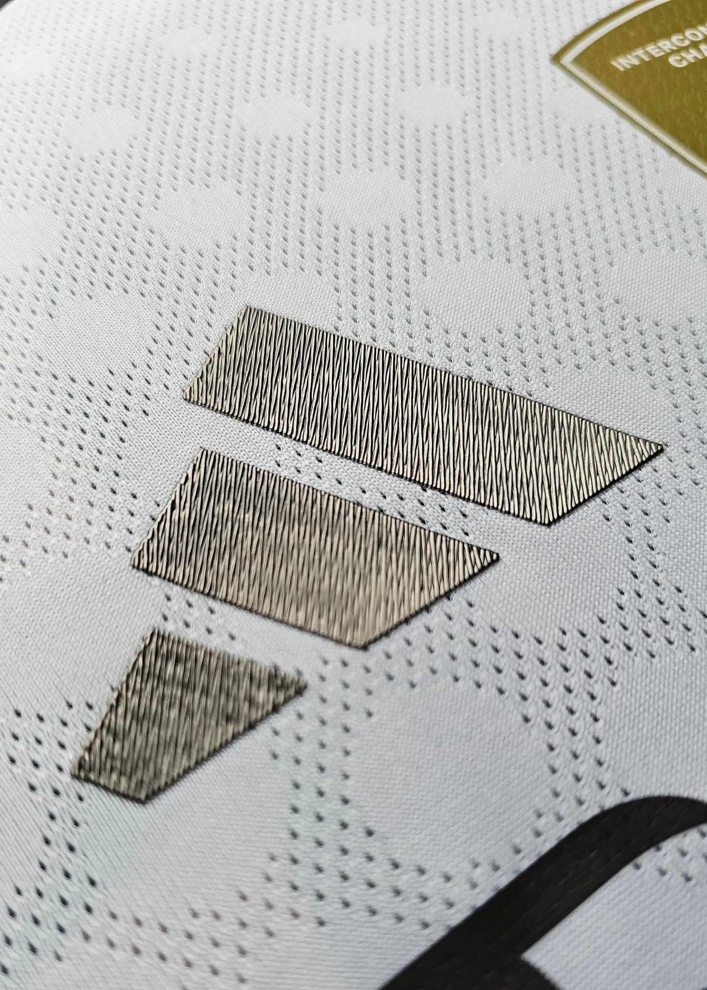 Close-up of the metallic sponsorship details on the white signed football shirt.