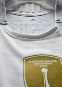 Close-up of collar displaying 'SLIM FIT' and adidas logo, with gold patch reading 'INTERCONTINENTAL CHAMPIONS 2024'.