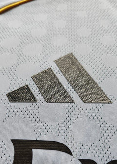 Close-up of the adidas logo in black on a textured white football shirt.