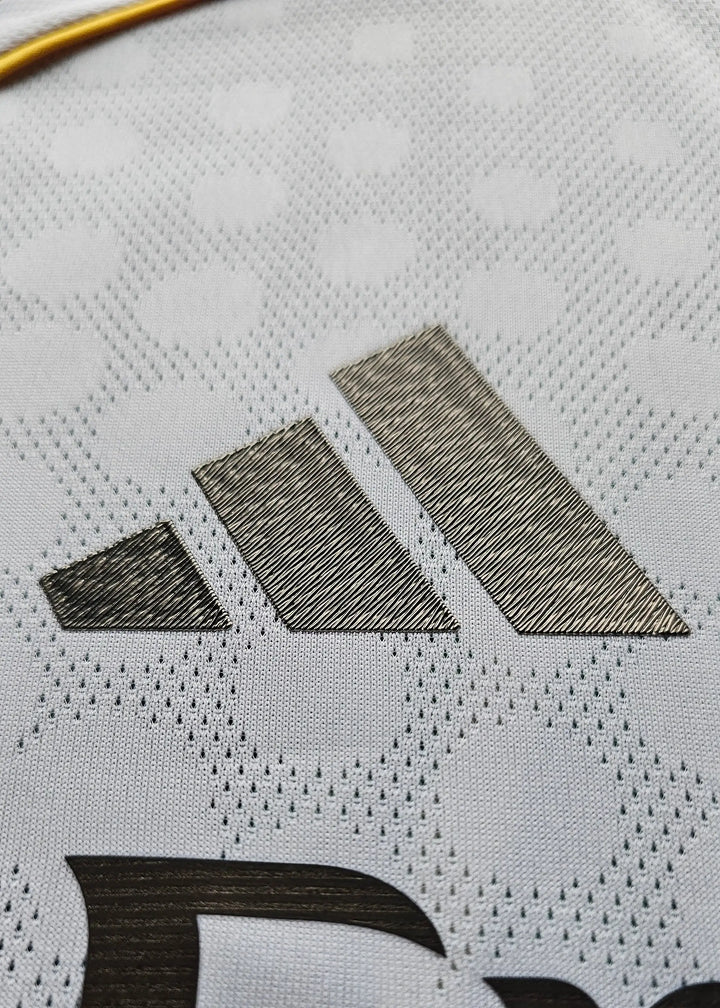 Close-up of the adidas logo in black on a textured white football shirt fabric.