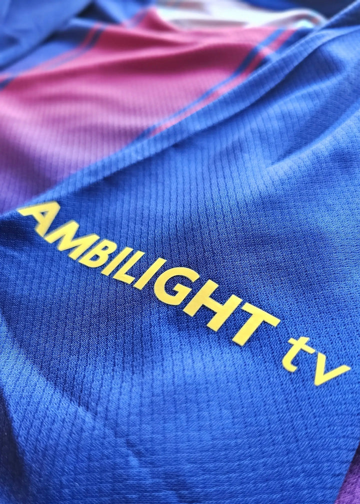 Close-up of a soccer jersey showing the yellow wordmark &