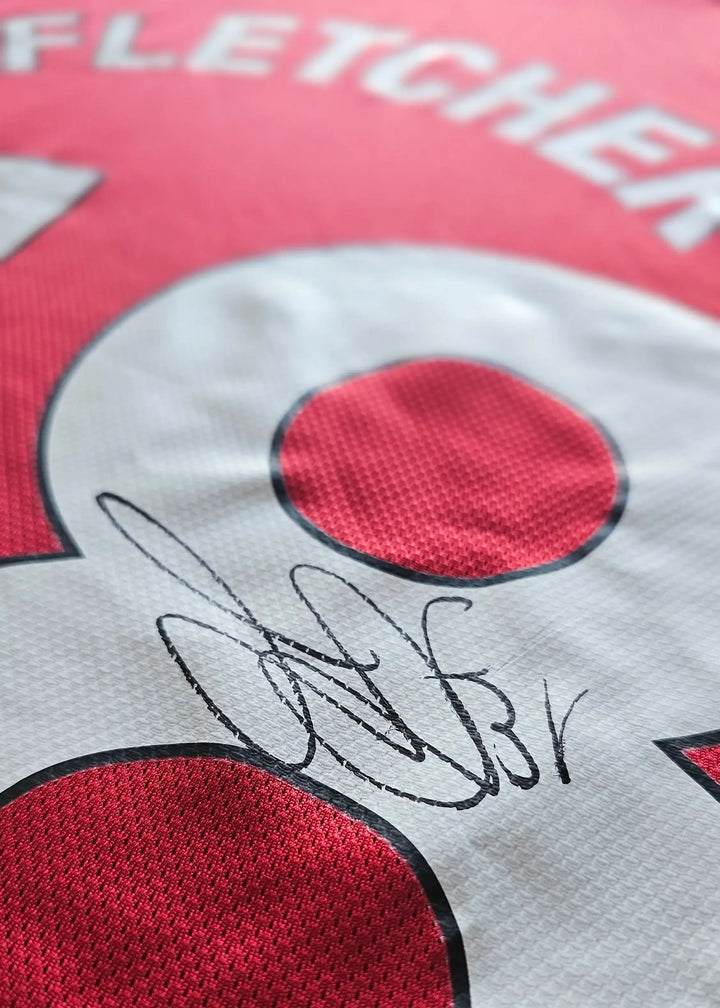 Close-up view showcasing the signature of Fletcher on the red Manchester United football shirt.