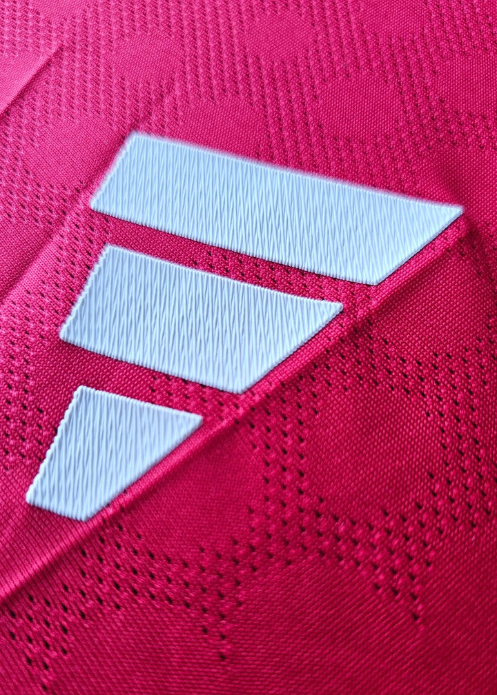 Close-up of red fabric featuring three white diagonal stripes on the football shirt.