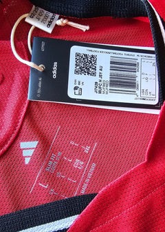 Internal label showing size L, care instructions, and adidas branding on red fabric.