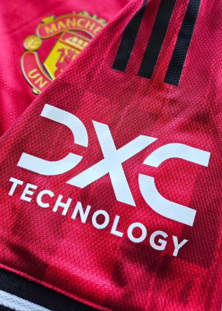 Close-up showing Manchester United crest and DXC Technology sponsor on red football shirt.
