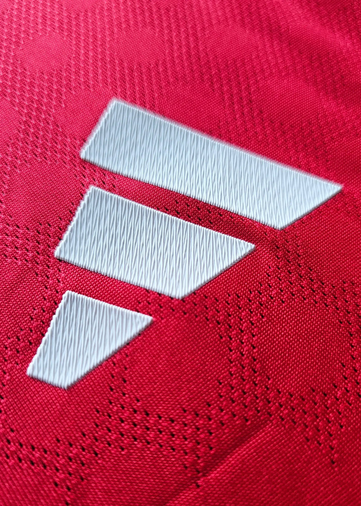 Close-up of the red fabric with three white adidas stripes and textured background.