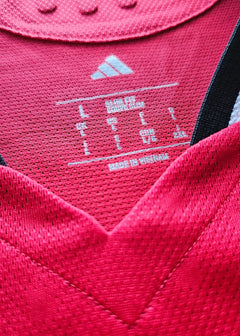 Size label showing L and "MADE IN VIETNAM" on red football shirt with adidas logo.