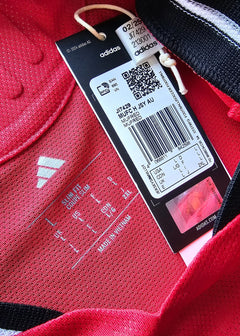 Label detail showing adidas branding and size information on a red football shirt.