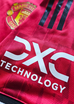 Close-up showing Manchester United crest and DXC Technology branding on a red football shirt.
