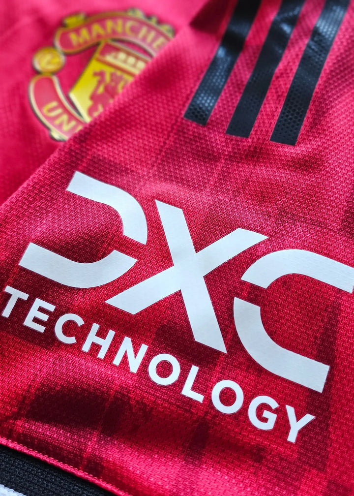 Close-up showing Manchester United crest and DXC Technology branding on a red football shirt.
