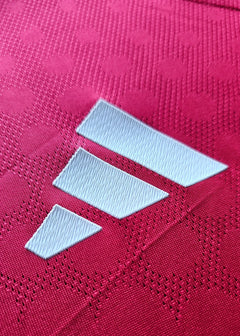 Close-up view of the adidas logo in white on a red football shirt.