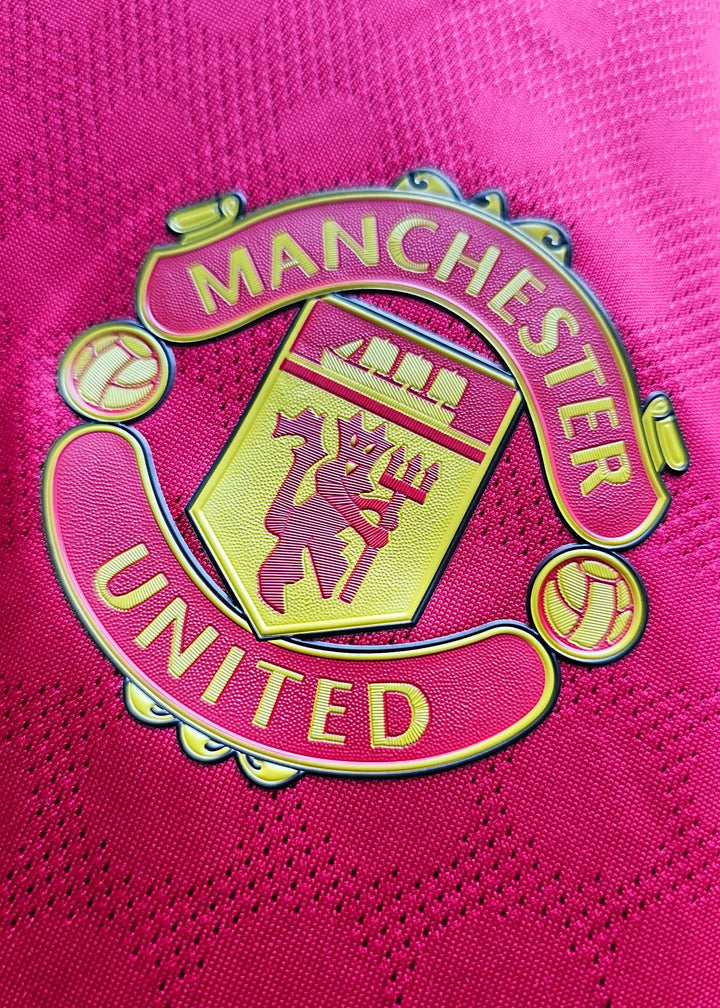 Crest detail of Manchester United featuring a golden lion on a red background.