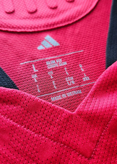 Detail of size label showing L, US L, and made in Vietnam on red football shirt.