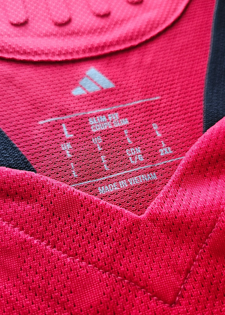 Detail of size label showing L, US L, and made in Vietnam on red football shirt.