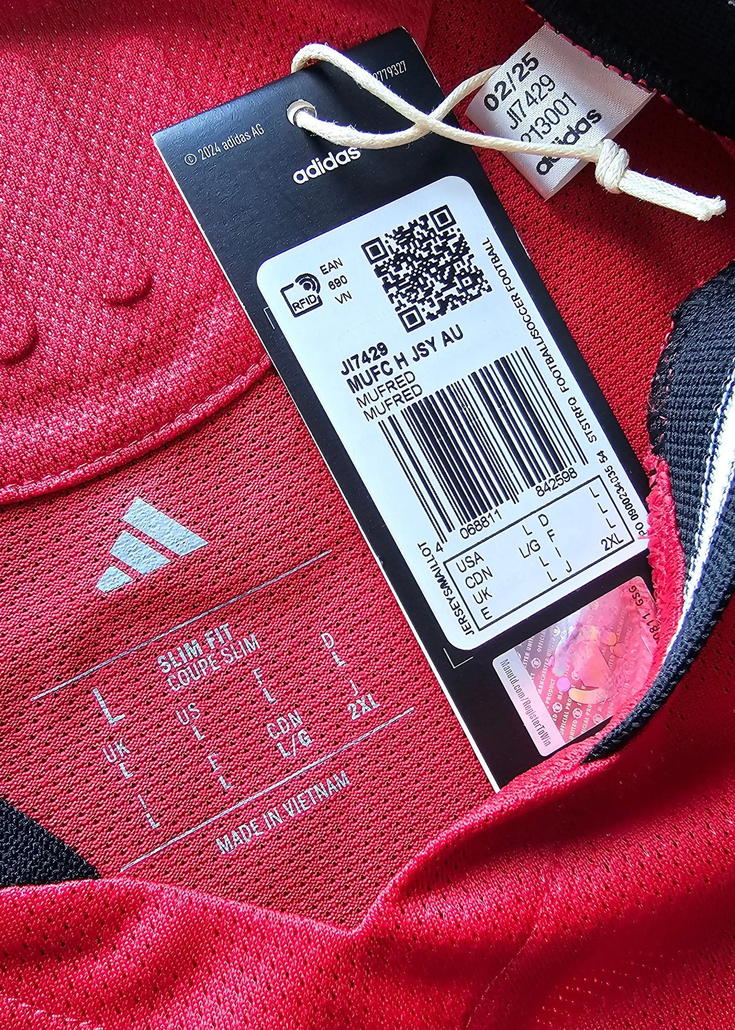 Label detail showing size information and adidas branding on a red football shirt.