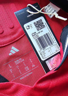 Label detail showing size information and adidas branding on a red football shirt.