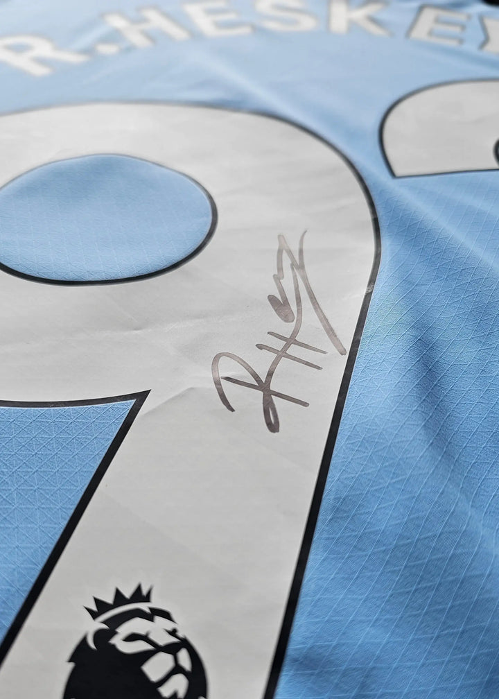 Detail showing No. 92 and signature of R. Heskey on a blue football shirt.