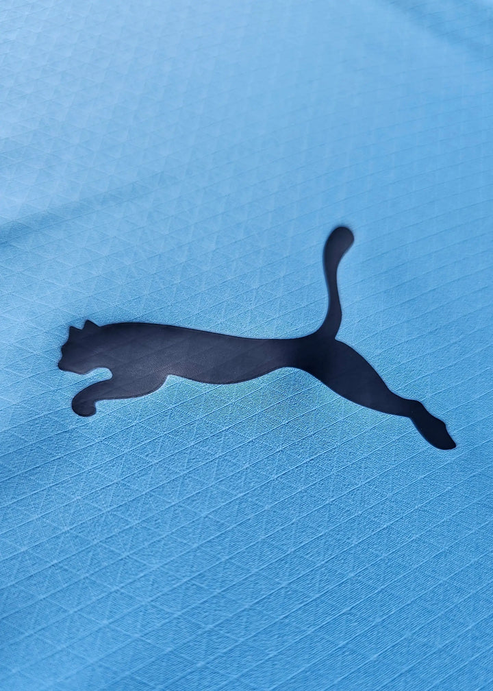 Close-up of the black Puma logo on a textured blue football shirt.