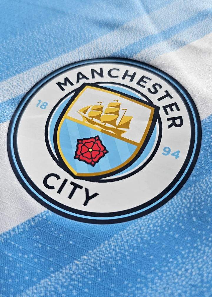 Detail of the Manchester City F.C. crest featuring a ship and rose in blue and white.