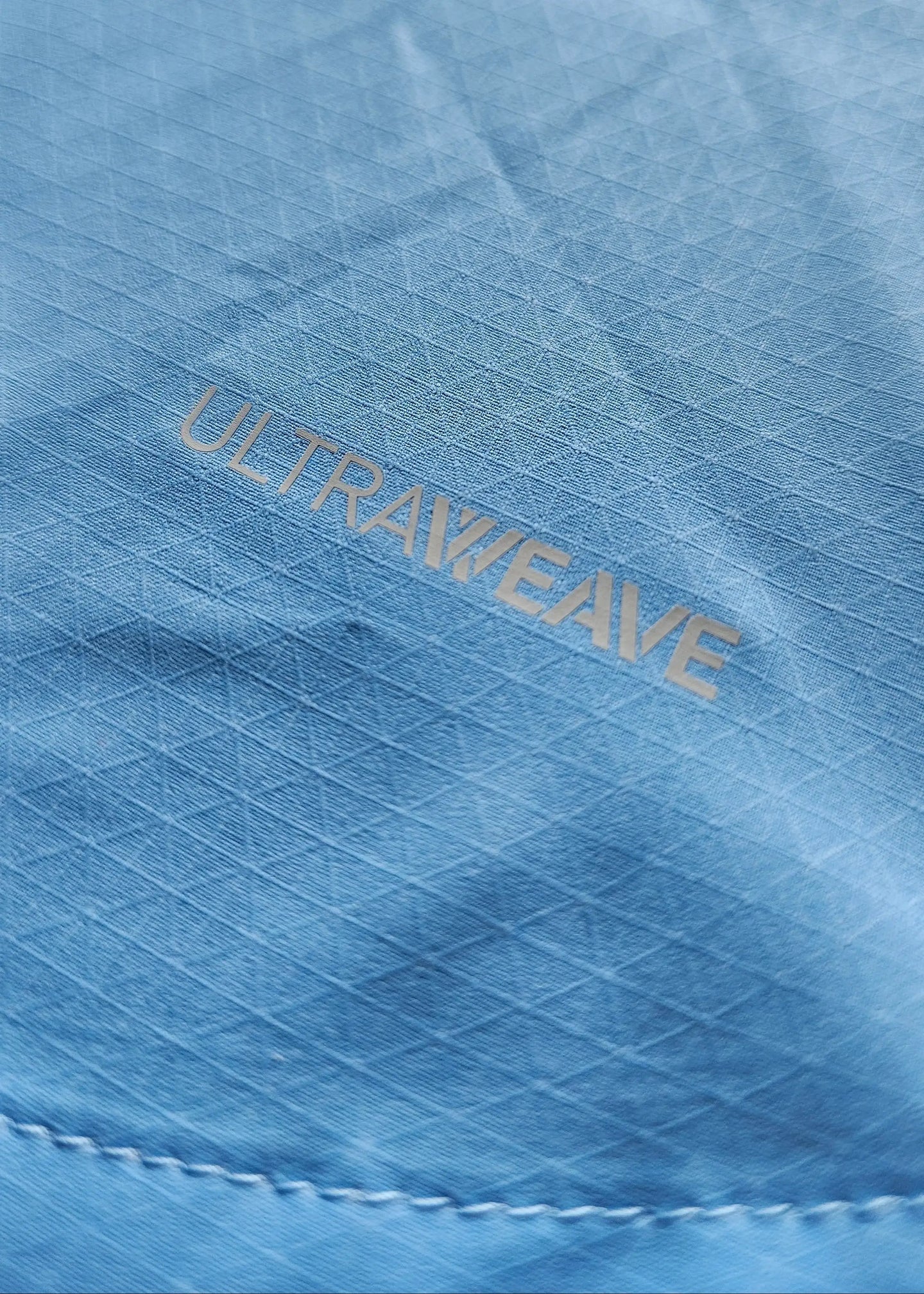 Close-up of blue fabric with embossed 'ULTRAWEAVE' pattern.