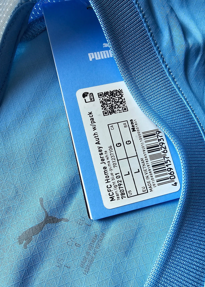 Light blue detail of Manchester City shirt showing Puma logo and size label L.