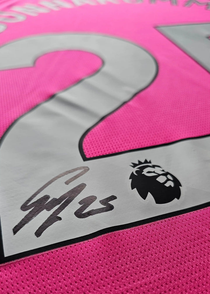 Close-up of signature on pink football shirt showing No. 25 and Premier League lion crest.