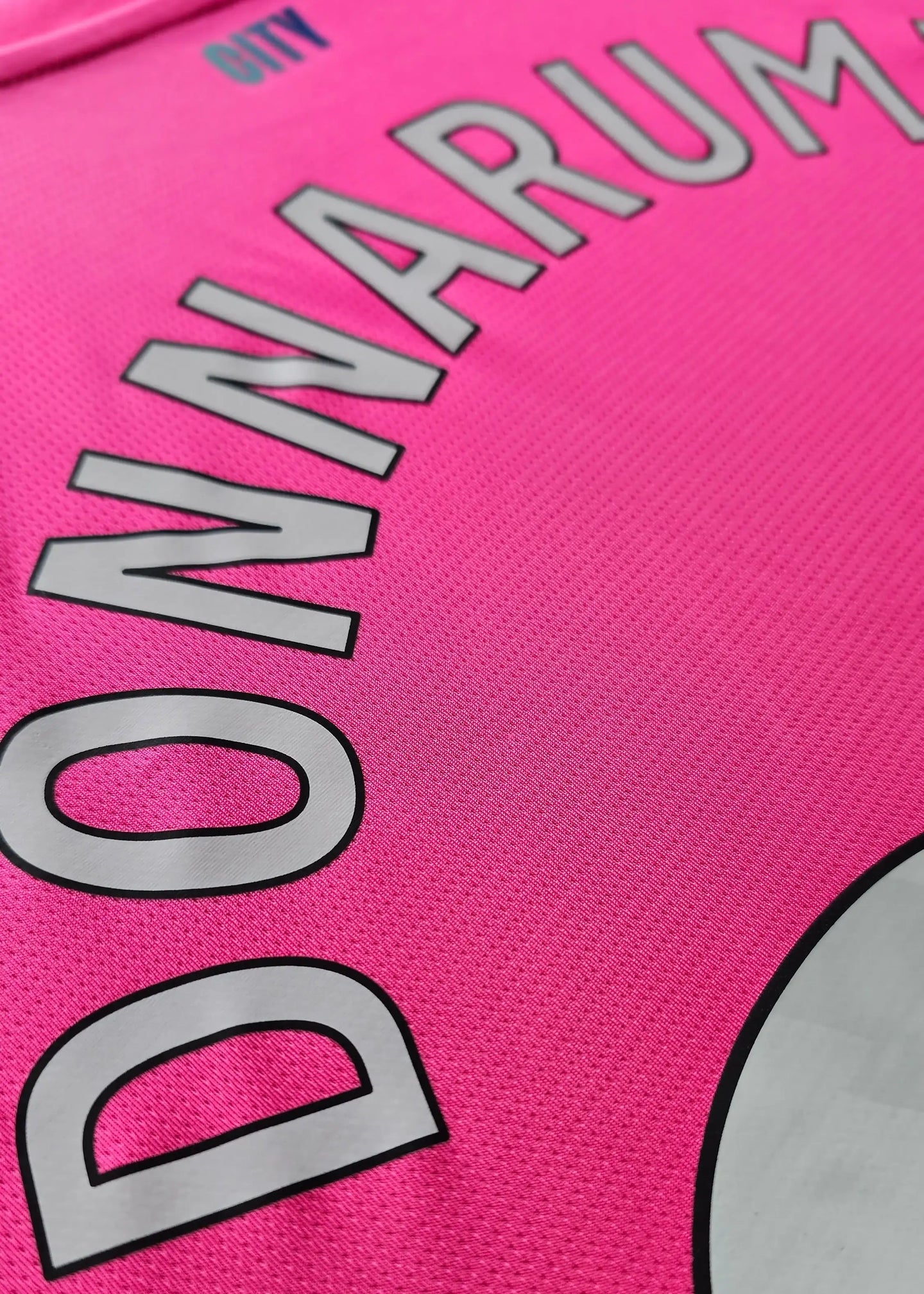 Close-up showing the name DONNARUMMA and CITY on a pink football shirt.