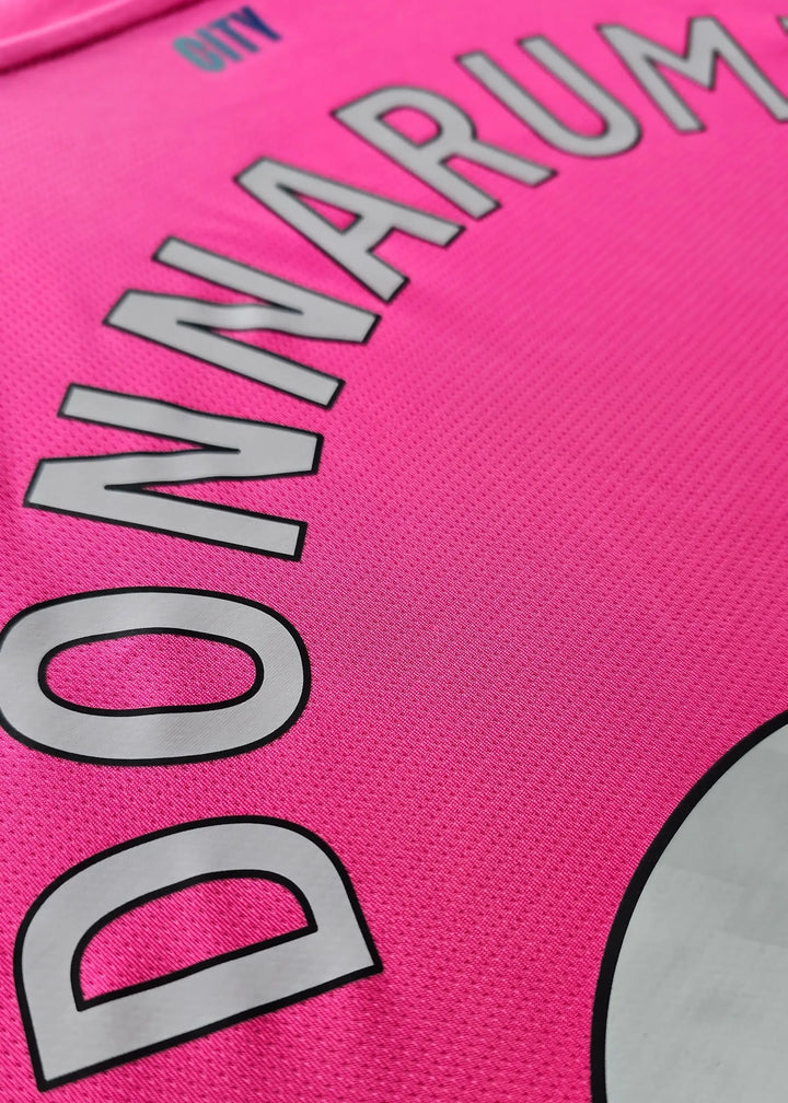Close-up showing the name DONNARUMMA and CITY on a pink football shirt.