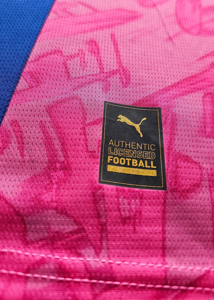 Close-up of the Puma tag on pink fabric, stating AUTHENTIC LICENSED FOOTBALL.
