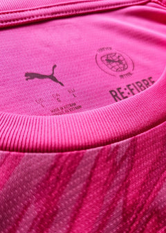 Close-up of pink fabric featuring Puma logo and RE:FIBRE branding details.