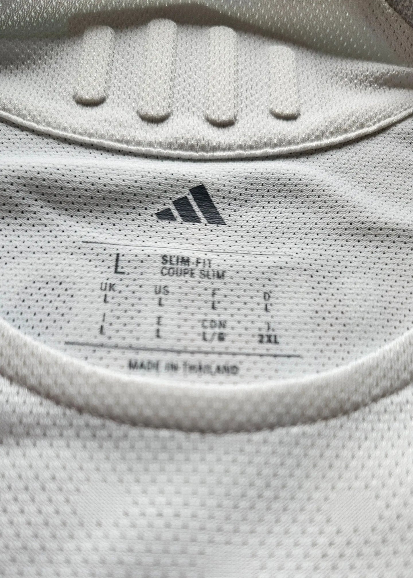 Label detail showing size L, slim fit, and adidas branding on a white football shirt.