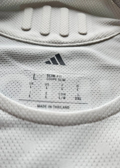 Label detail showing size L, slim fit, and adidas branding on a white football shirt.