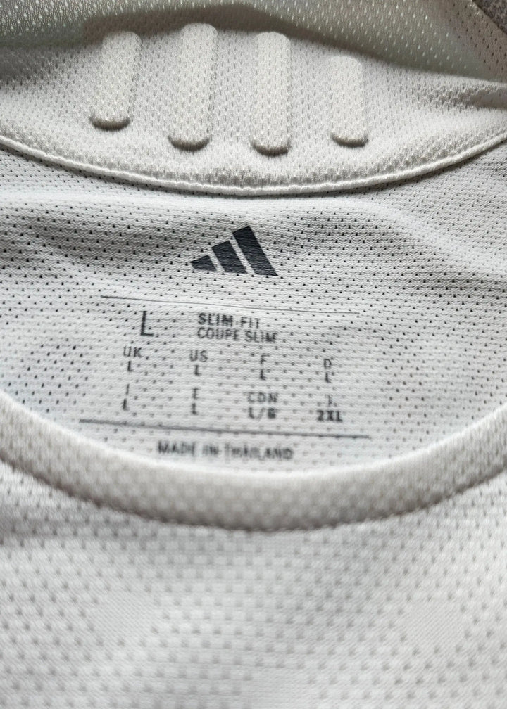 Label detail showing size L, slim fit, and adidas branding on a white football shirt.
