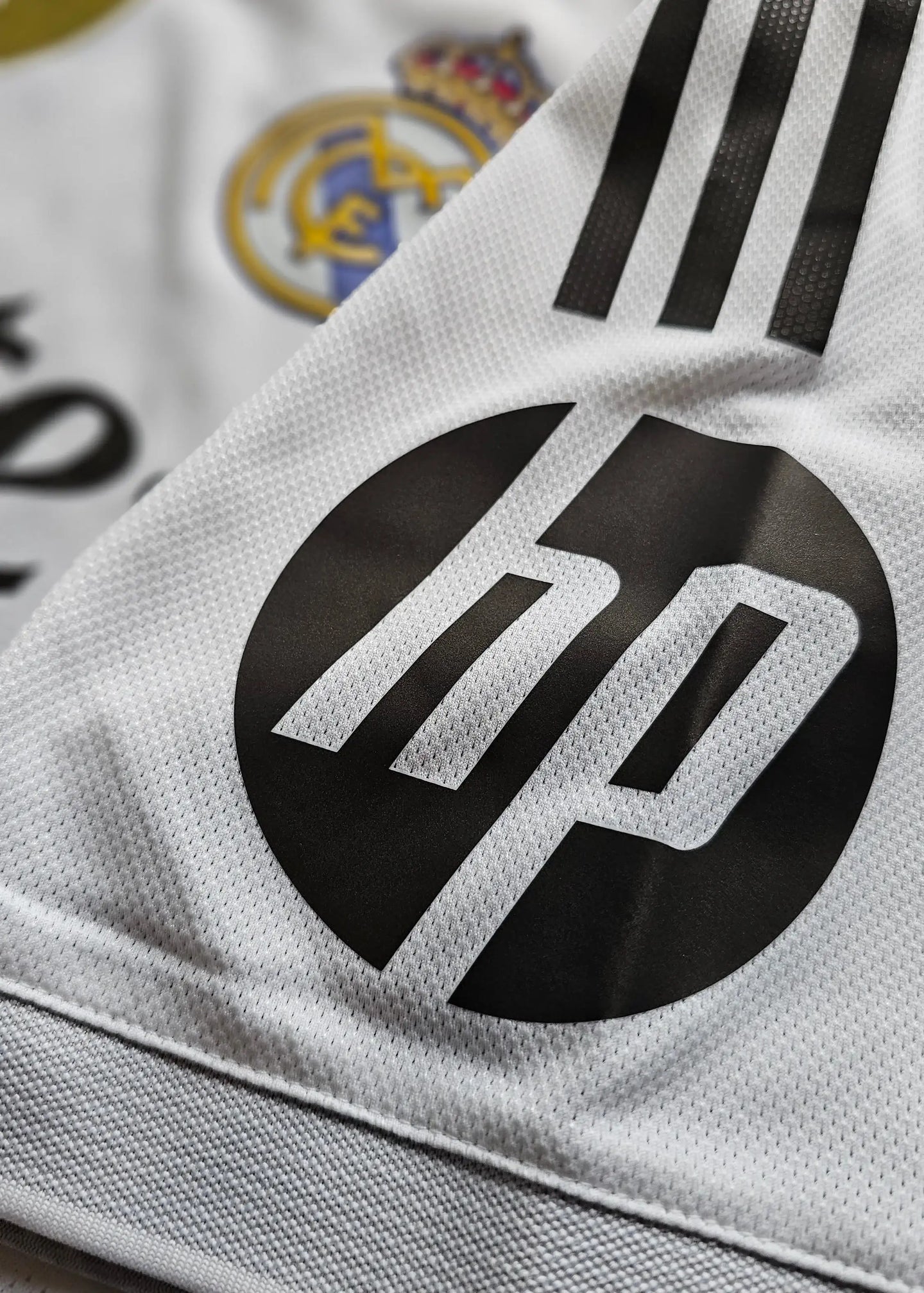 Close-up detail showing Real Madrid crest and HP sponsor logo on a white football shirt.