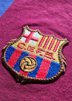 Close-up of the FC Barcelona crest featuring red and blue stripes and gold detailing.