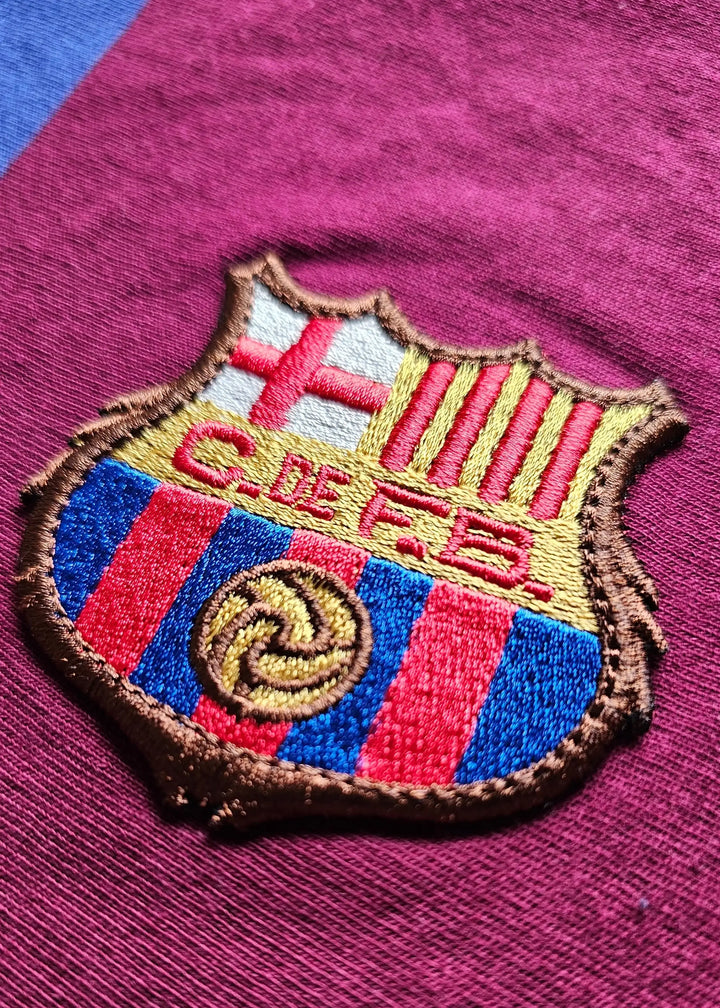 Close-up of the FC Barcelona crest featuring red and blue stripes and gold detailing.
