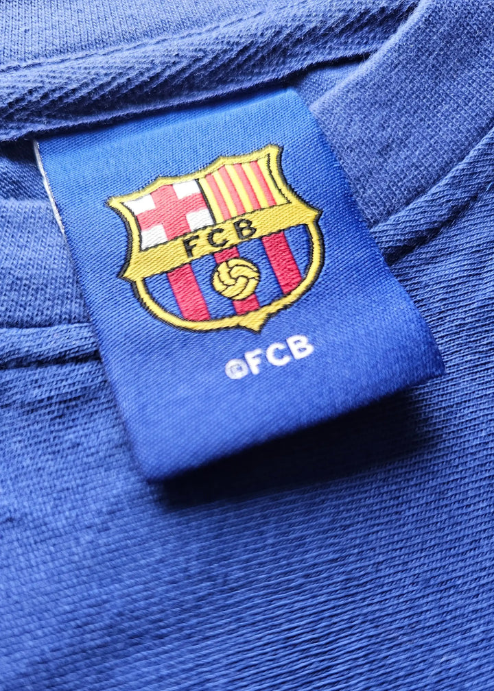 Close-up of FC Barcelona crest with FCB lettering and embroidered details on a navy background.