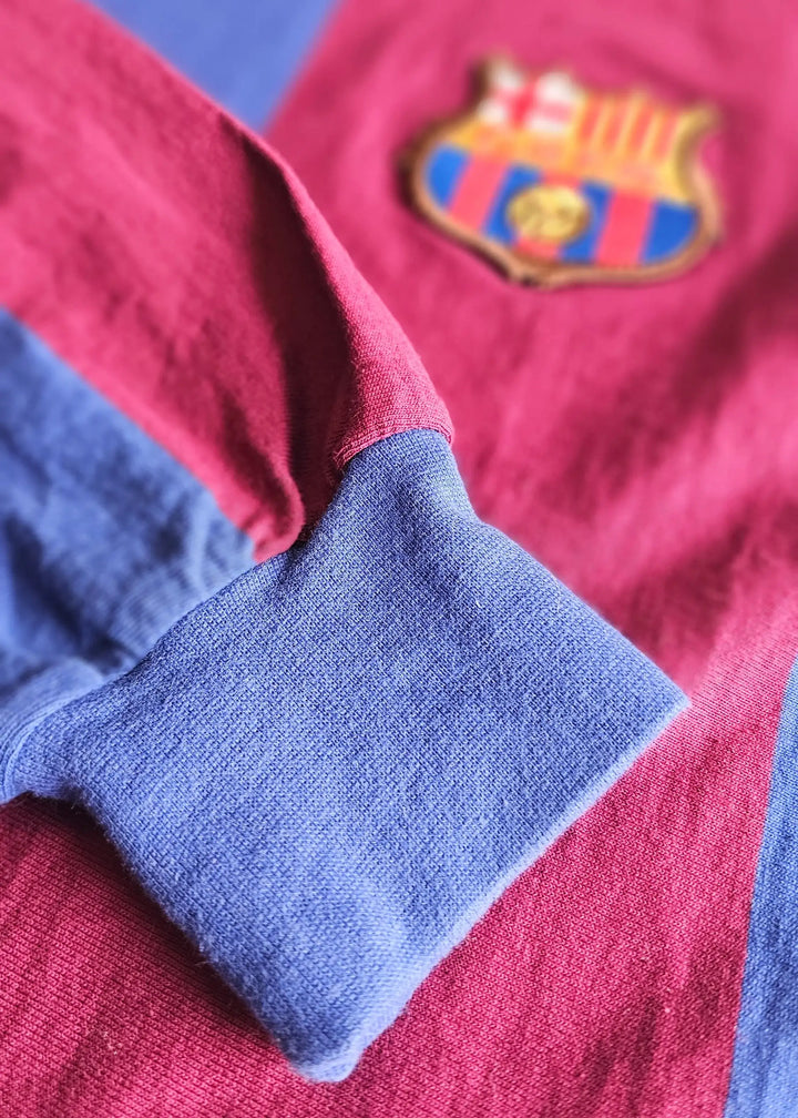 Cuff detail in blue fabric with red background and FC Barcelona crest visible.