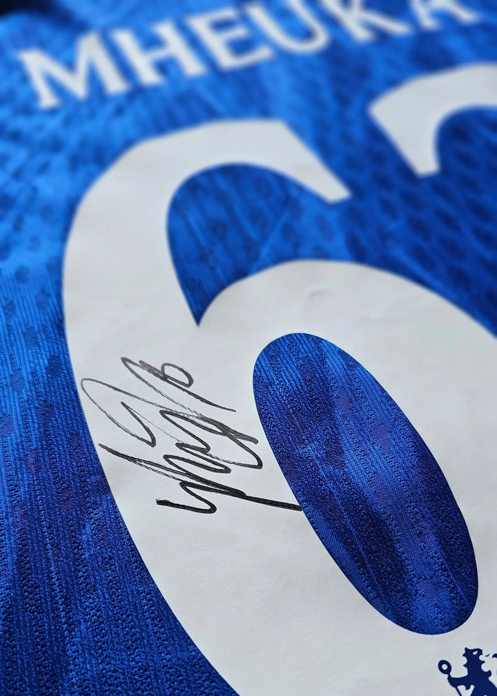 Detail view of blue football shirt showing the number 6, name MHEUKA, and signature.