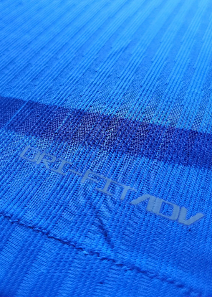 Close-up of blue fabric showing DRI-FIT ADV text with textured pattern.