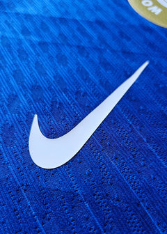 Close-up of white Nike logo on blue fabric background with textured pattern.