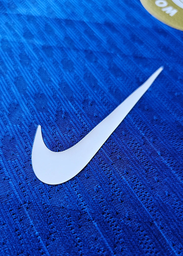 Close-up of white Nike logo on blue fabric background with textured pattern.