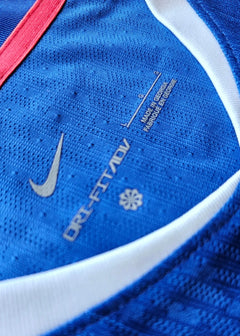 Close-up of label featuring Nike logo, ORI-FIT ADV text, and care instructions on blue shirt.