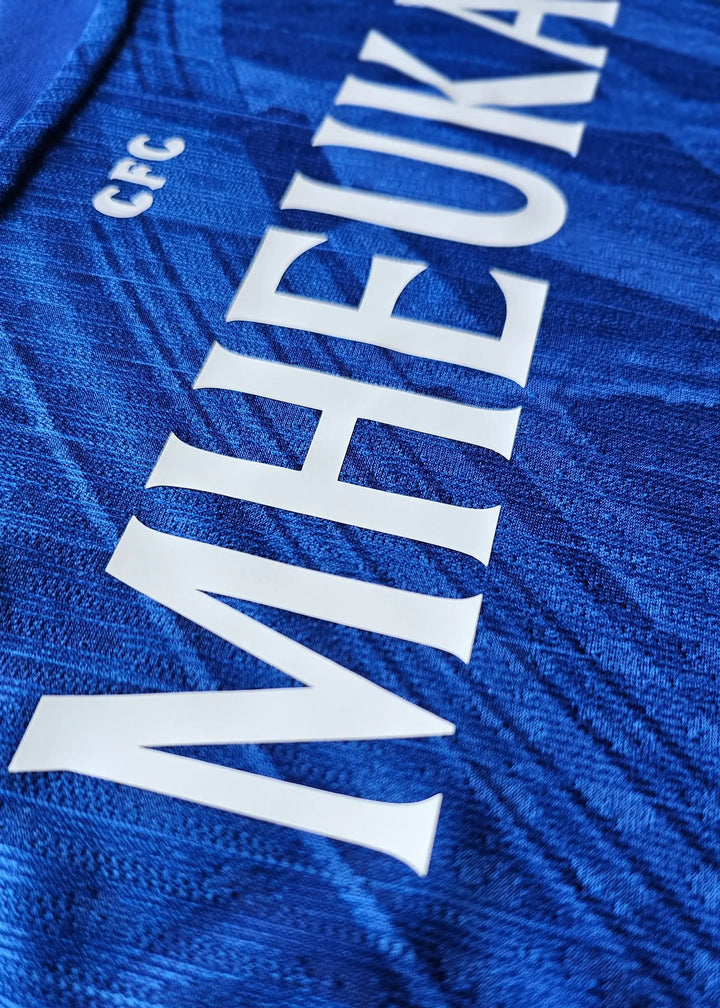 Close-up view showing the name 'MHEUKA' and 'CFC' on a blue football shirt.