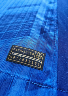 Close-up showing the 'ENGINEERED' tag and 'MB178311GL' on a blue football shirt.